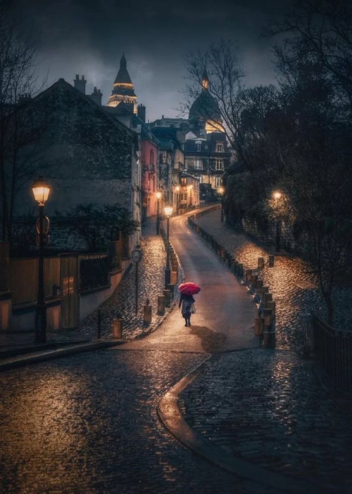 Une personne avec un parapluie rouge avancent dans les rues pavées d’une ville à la nuit tombée. C'est sur ce somptueux travail de by Michael Sidofsky que je vous adresse mes meilleurs voeux pour la #nuit à venir.
