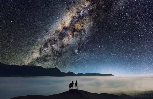 La Voie lactée illuminée dans un ciel étoilé, avec des étoiles brillantes et des nuages de gaz interstellaires. 