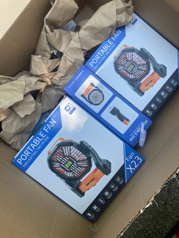 Top view of a cardboard box with stacks of portable, rechargeable fans in blue boxes.