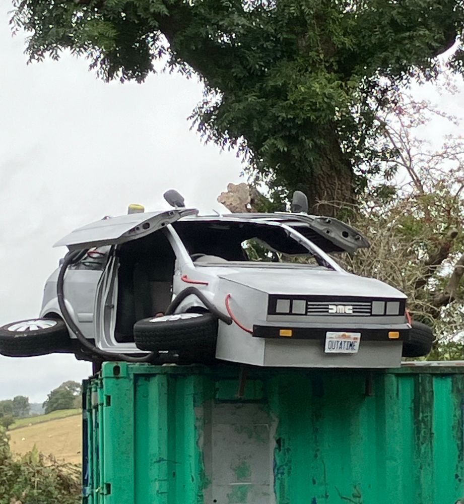 Model of a DeLorean car from the film Back to the Future sitting on top of a crate in the countryside 