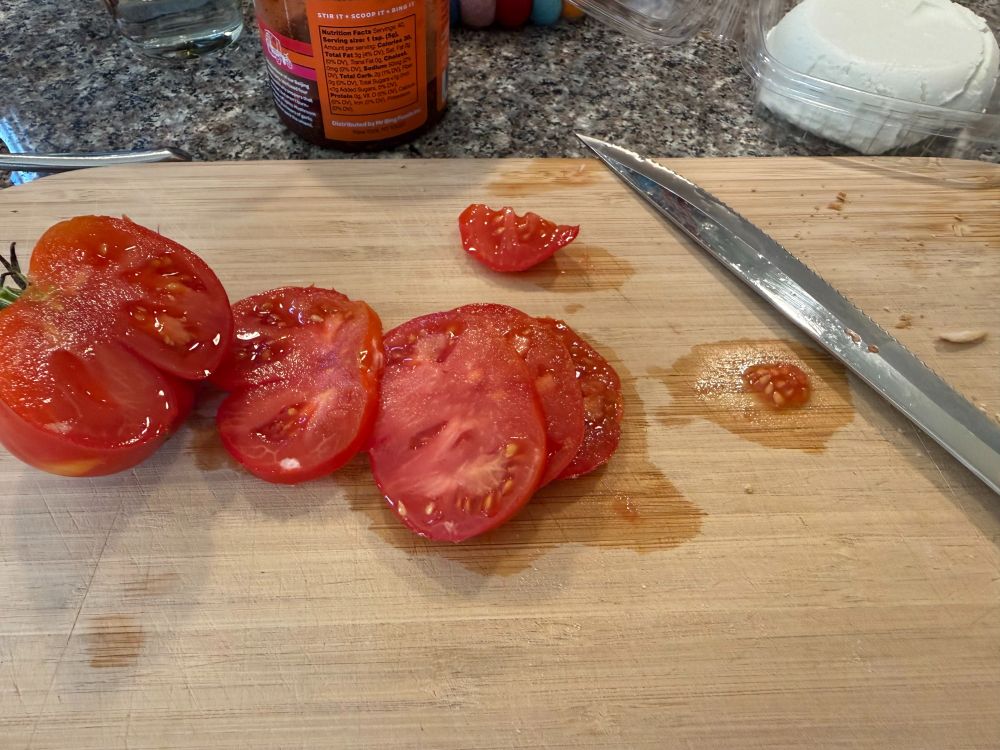 Dark red slices of fresh tomato on a cutting board.