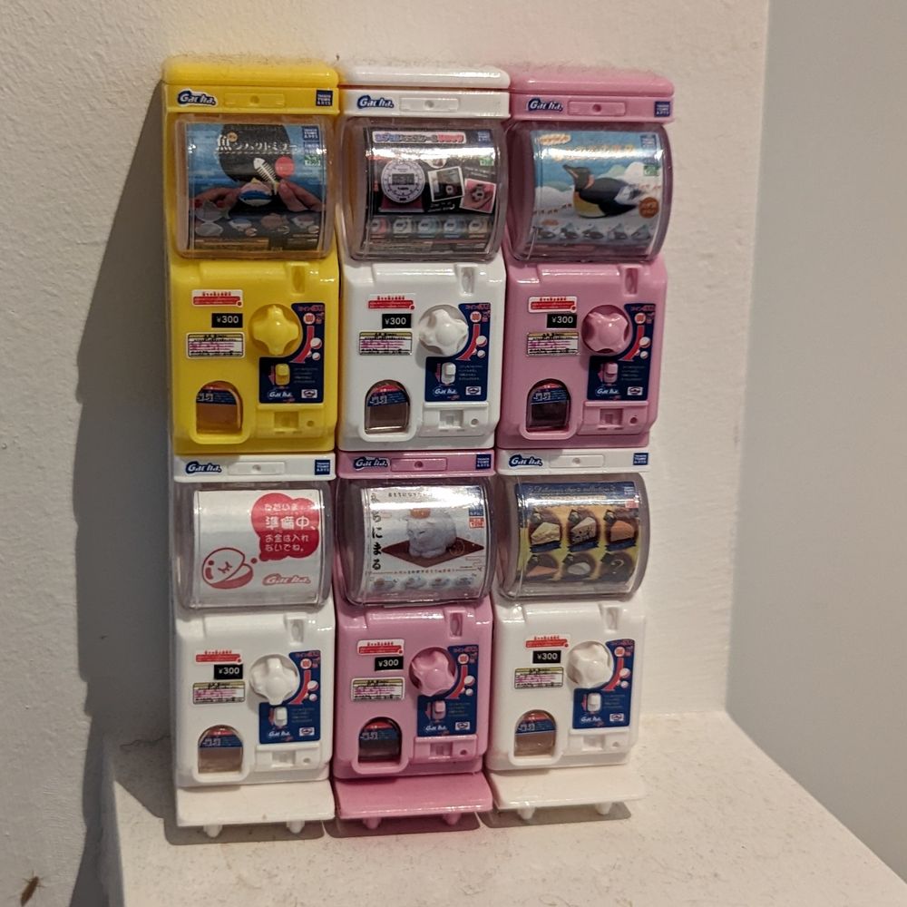 A stack of six mini gachapon machines that are themselves from gacha