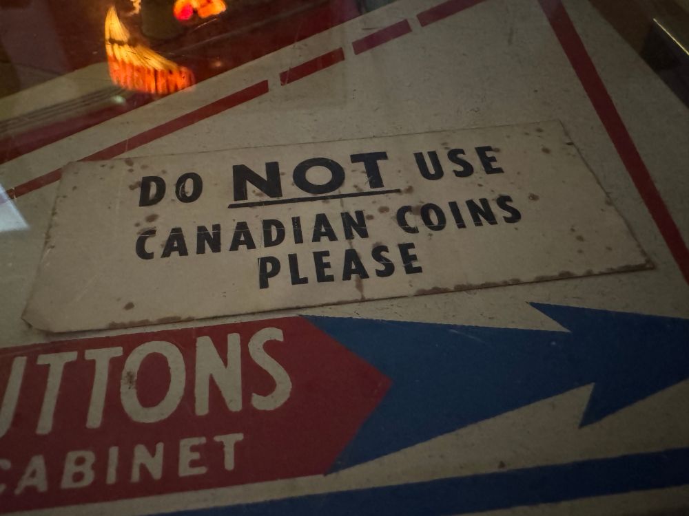 A sticker on a vintage pinball machine that reads: Do NOT Use Canadian Coins Please