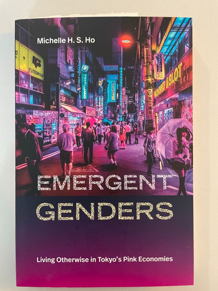 Book cover of a busy Tokyo street scene at night in pink and purple shades with the title, Emergent Genders in sparkling silver and gold