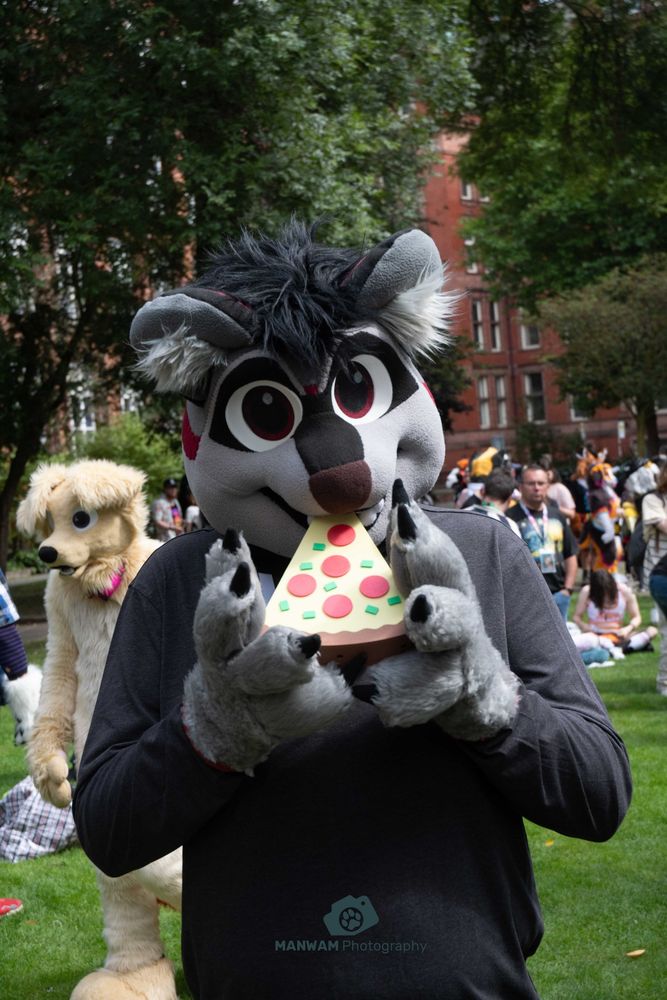 Sy in partial suit with a pizza-shaped fan in their muzz, taken by Manwam