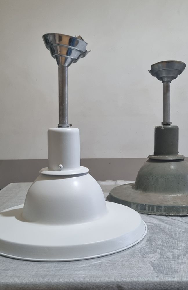Sur une table, deux suspensions industrielles. Celle de droite est dans son jus ( à savoir 25 ans dans une vieille réserve), celle de gauche est nettoyée, dégraissé, repeinte en blanc. 