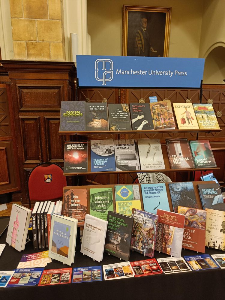 Photograph of the Manchester University Press conference stand at the ASA 2025, displaying a selection of sociology, anthropology and geography books as well as posters and marketing materials for their key book series.