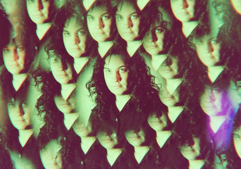 portrait on 35mm done with a prism filter. This one is of my face! There are many jesses in a radial pattern coming from the center. There is a greenish light shining straight on my face. The shadows/dark areas are a maroon. 