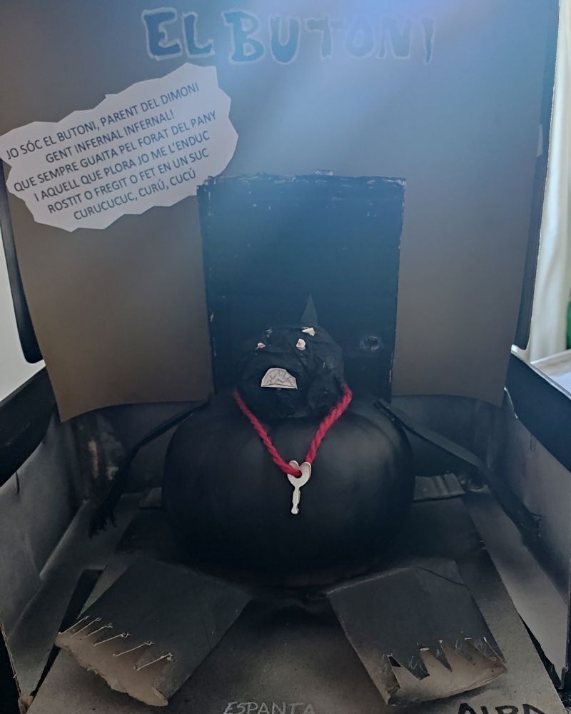 Un ninot fet amb una carabassa. Es un dimoni gros, negre i amb una claueta penjada al coll (quasi no té coll)
Darrere té una porta i n'hi ha un text.
"Sóc el Butoni, parent del dimoni. Gent infernal, infernal, que sempre guaita pel forat del pany. 
I aquell que plora jo me l'enduc rostit O fregit o fet en un suc.
Curucucuc curu cucu