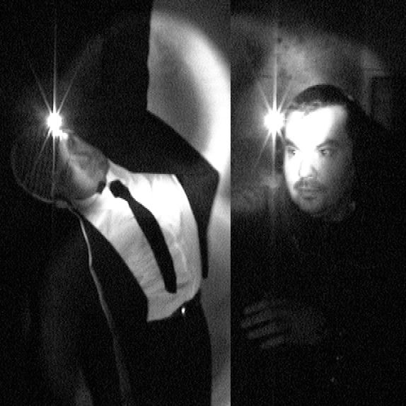 Black-and-white split-screen photo showing two men wearing headlamps in a dark environment. On the left, a man in a white shirt, black tie, and dark suit leans dramatically backward with one arm raised, as the light from his headlamp shines directly at the camera, creating a bright flare. On the right, another man with darker clothing gazes slightly to the side, his face illuminated by his own headlamp. Both scenes are dimly lit, with shadows and soft fog-like textures in the background, creating a mysterious and theatrical atmosphere.
