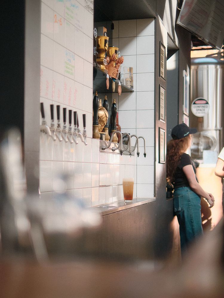 The back bar of main st brewing where an amber coloured pint of cask beer settles, waiting to be topped up. 