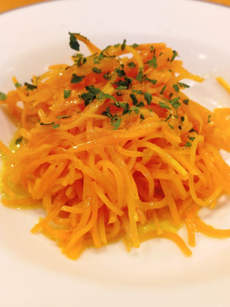 白いお皿に盛られた千切りの人参サラダの写真。上に乾燥パセリがかかっている。