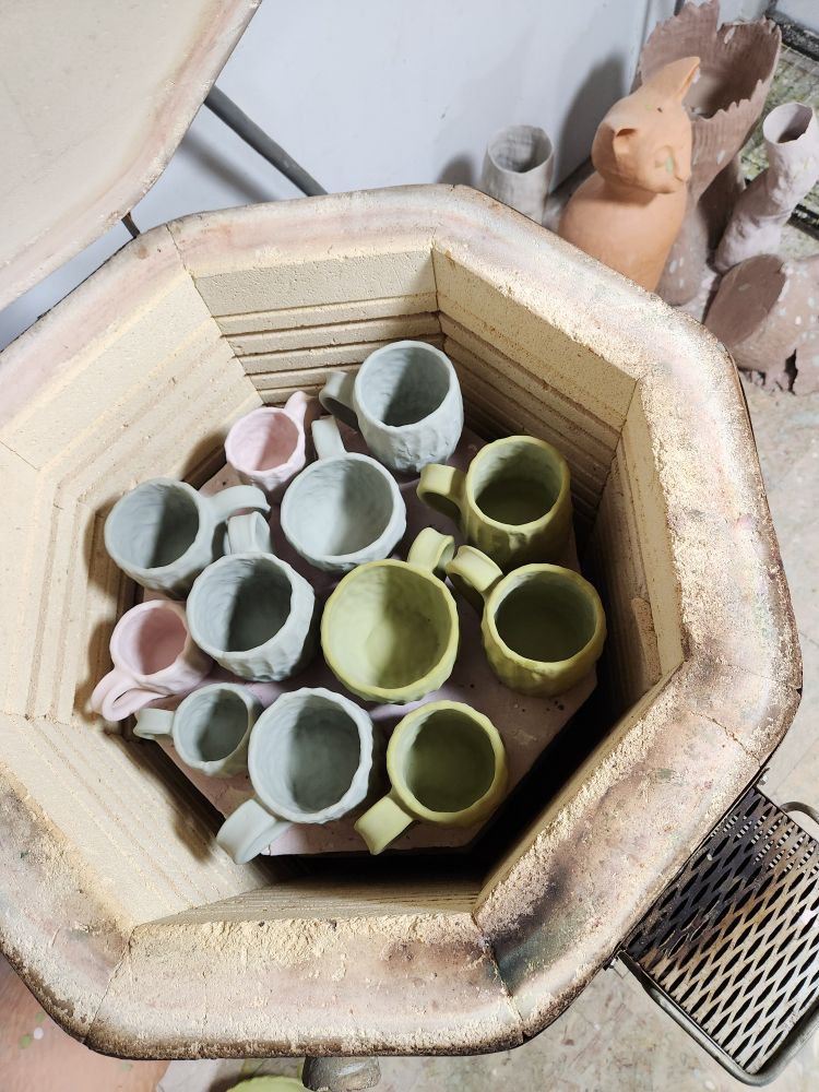 Glazed mugs in a kiln ready to be fired.