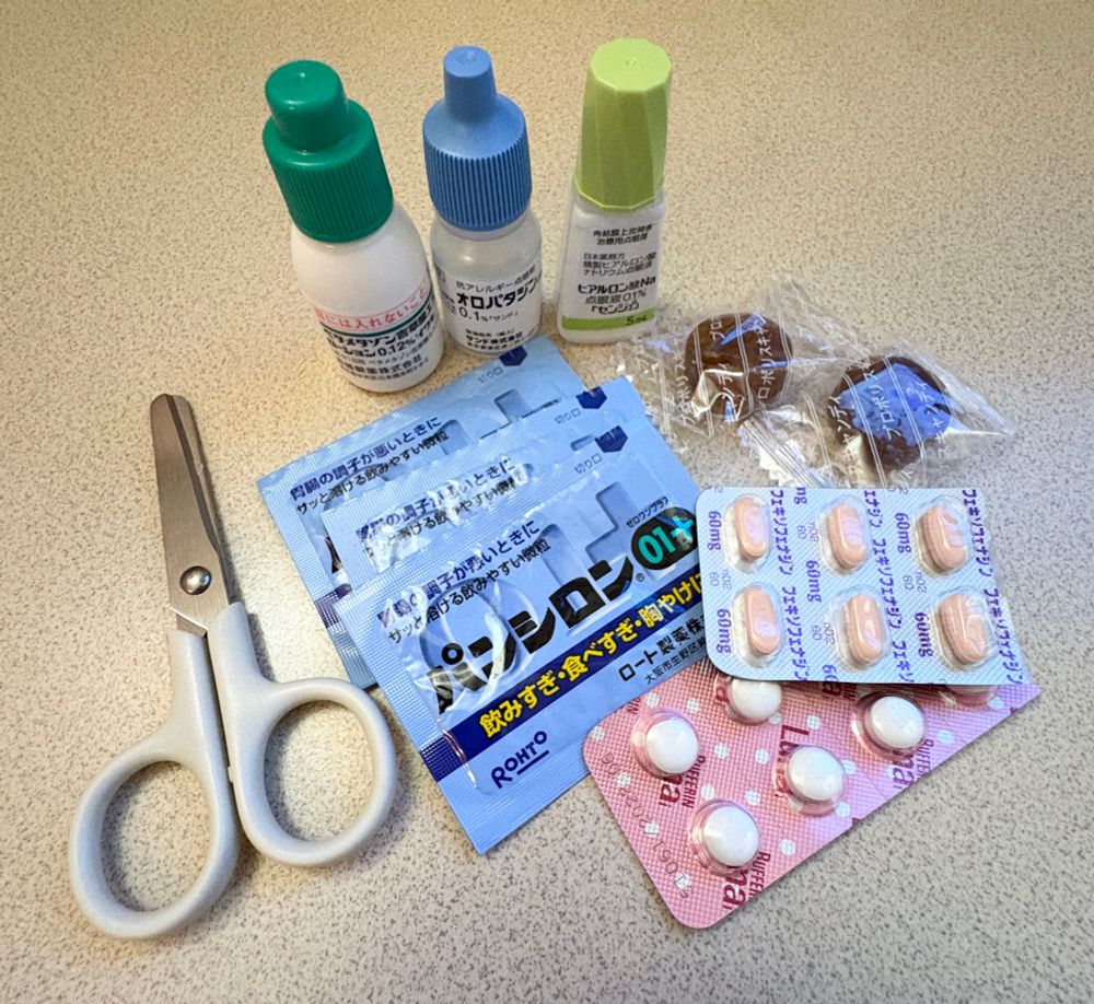 テーブルの上に置かれた小さなハサミ、目薬、塗り薬、飲み薬、のど飴。