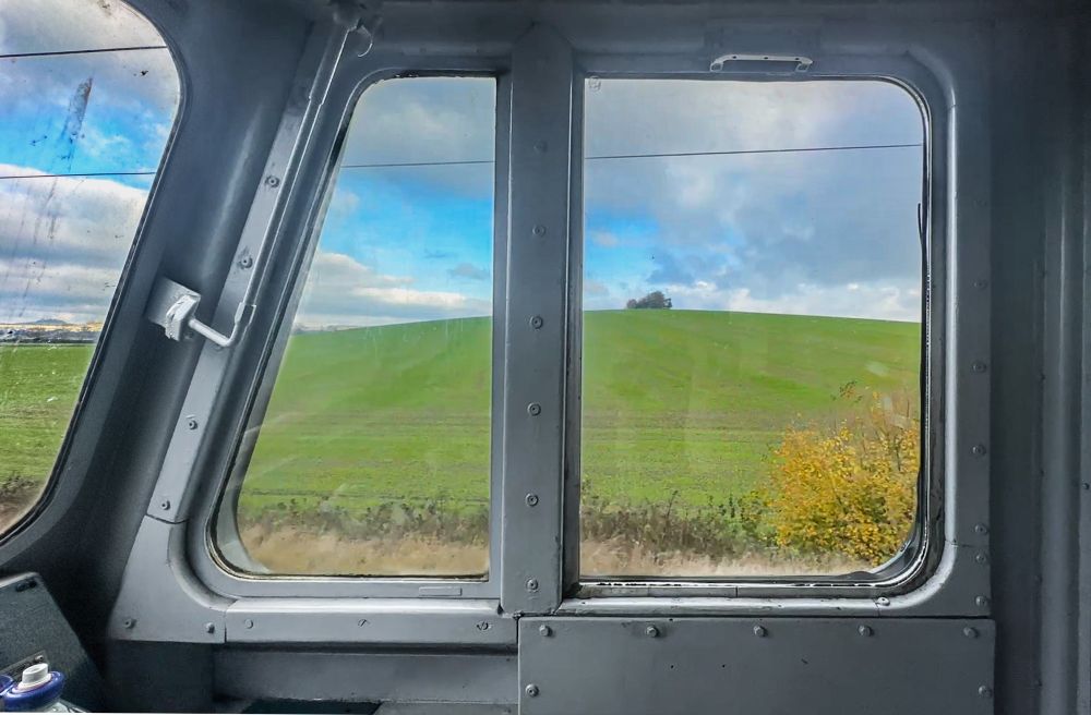 Side view from the cab of a UK Class 50 mainline locomotive out to green hills beyond