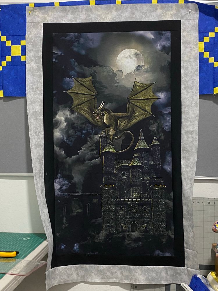 Adding the border onto this dragon sitting upon the top turret of a gothic castle.  It’s done in grays, black, beige, and a touch of gold.