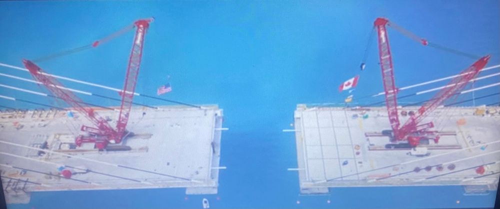 Suspension Bridge, being built nearly complete left side USA flag right side Canada flag