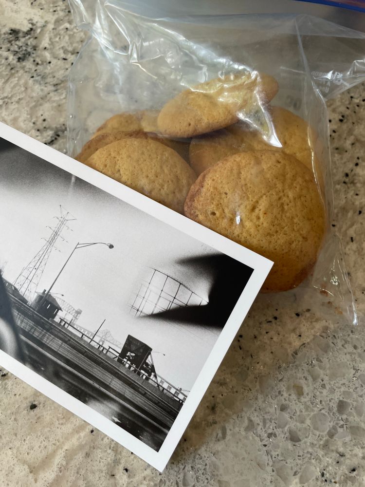 Photo of black and white postcard and a ziplock bag of cookies. 