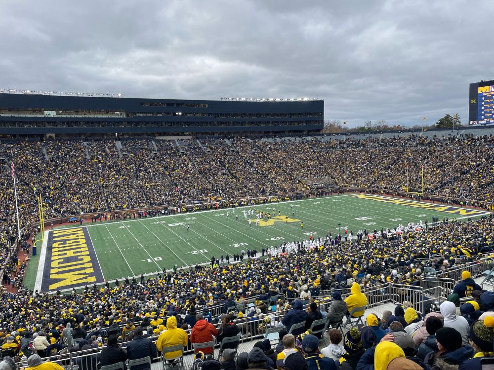 View of the football field at Michigan Stadium on a cold fall day, with the stands packed with fans. 