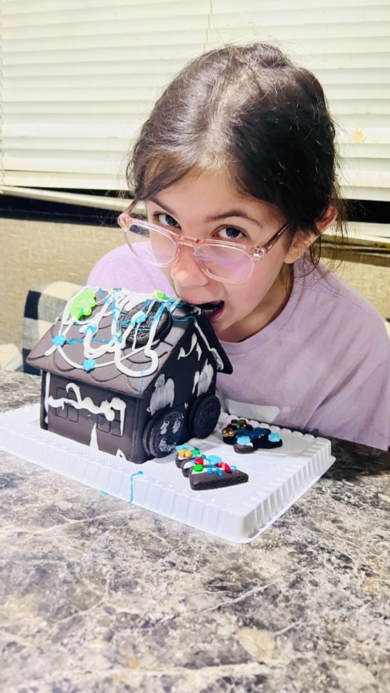 E poses as if she's taking a big bite out of the roof of her Oreo gingerbread house.  The house has blue and white icing on it - but most of the candy decorations went straight to the stomach!