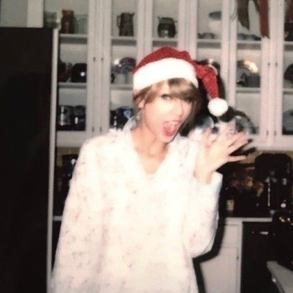 taylor swift white sweater and santa hat waving