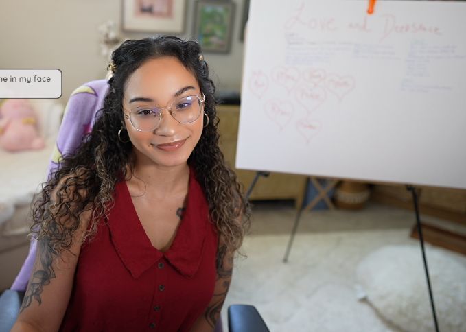 lorie wearing a red dress with a love and deepspace posterboard in the background. it details plot points with community names also on the bottom