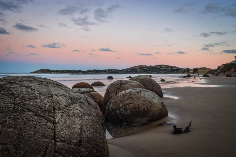 The Moeraki Boulders. The story is these are gourds thrown overboard from the sinking Āraiteuru, and they live on the beach between Kurinui and Moeraki. Ancient, beautiful spherical boulders little the sandy shore with the Moeraki peninsula behind it.