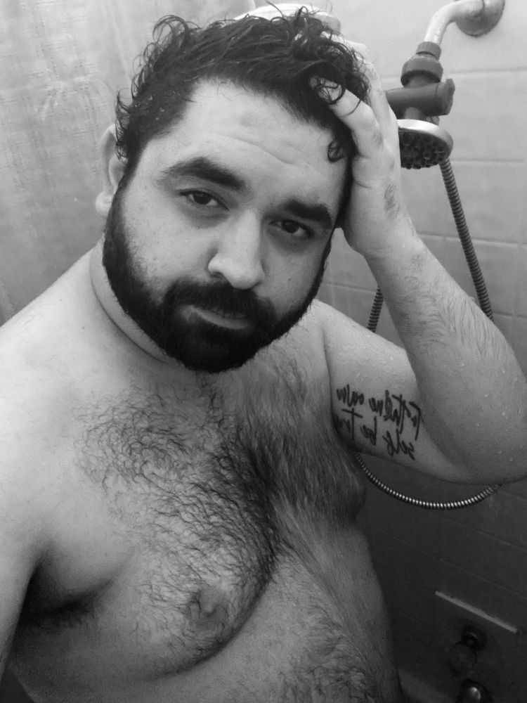 Black and white picture of bear in the shower, wet and torso is shown