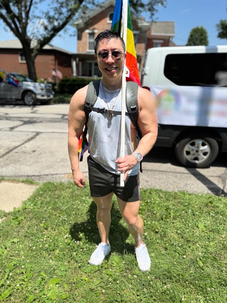 Cud make with gray tank top and black shorts carrying a flag In front of a van 