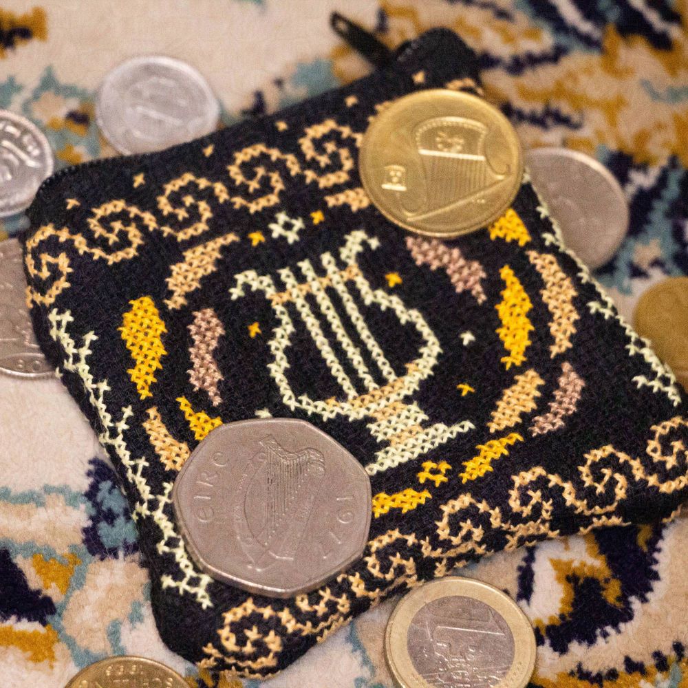 A photo of an embroidered club purse on a carpet and surrounded by come from various countries