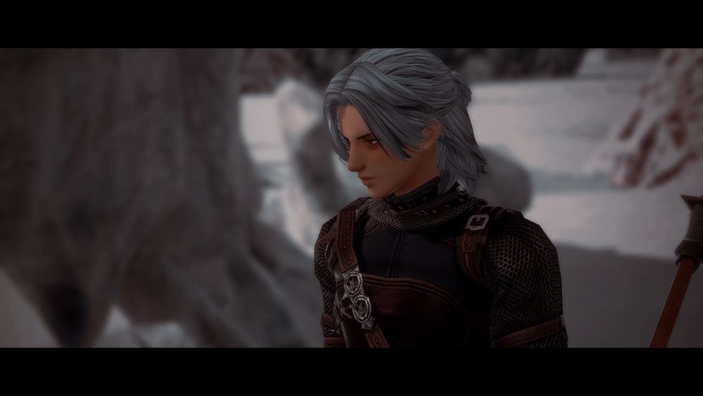 a closeup of wilka. he wears a neutral expression and has dark circles under his eyes, the snowy vast landscape stretches out behind him.