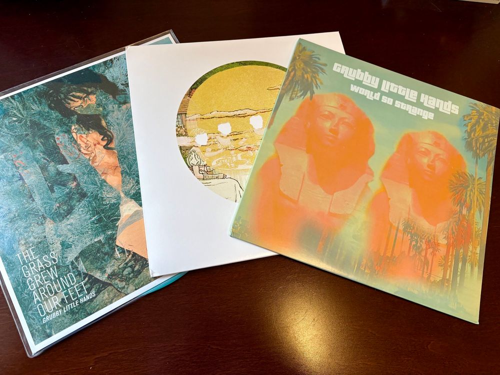 Album covers for three records by Grubby Little Hands: World So Strange, Garden Party, and The Grass Grew Around Our Feet.