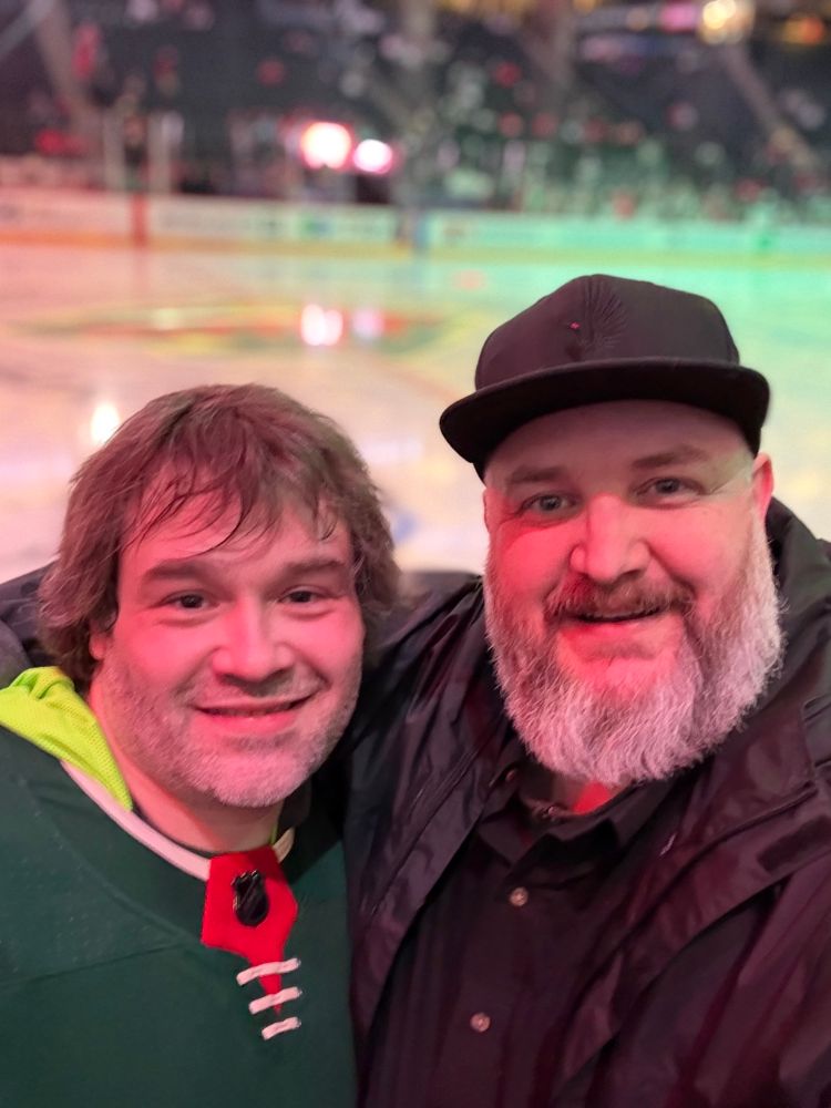 Two men in front of a hockey rink
