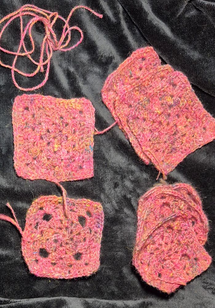 Eight pink handspun crochet motifs set on a black background 