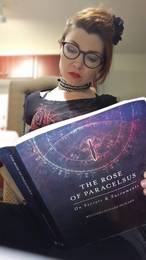 Woman in black holds a copy of "The Rose of Paracelsus" by Leonard Pickard