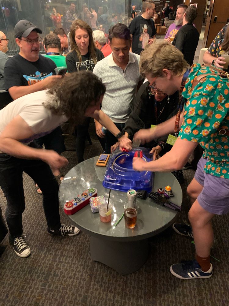 Some people playing Beyblades in a crowded hotel bar 