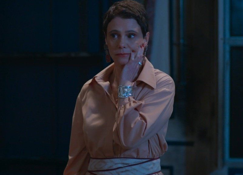 Imagem estática da personagem "tia Celina", da novela Vale Tudo, com uma expressão neutra, levando a mão ao rosto. 