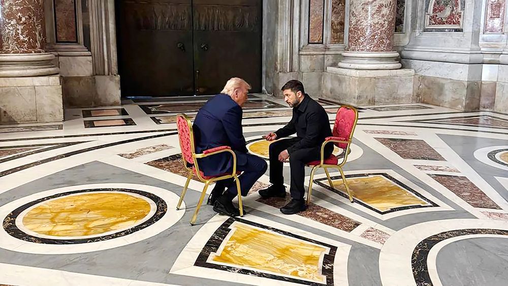 A photo of Trump and Zelensky sitting face to face on chairs in a large empty room in the Vatican.