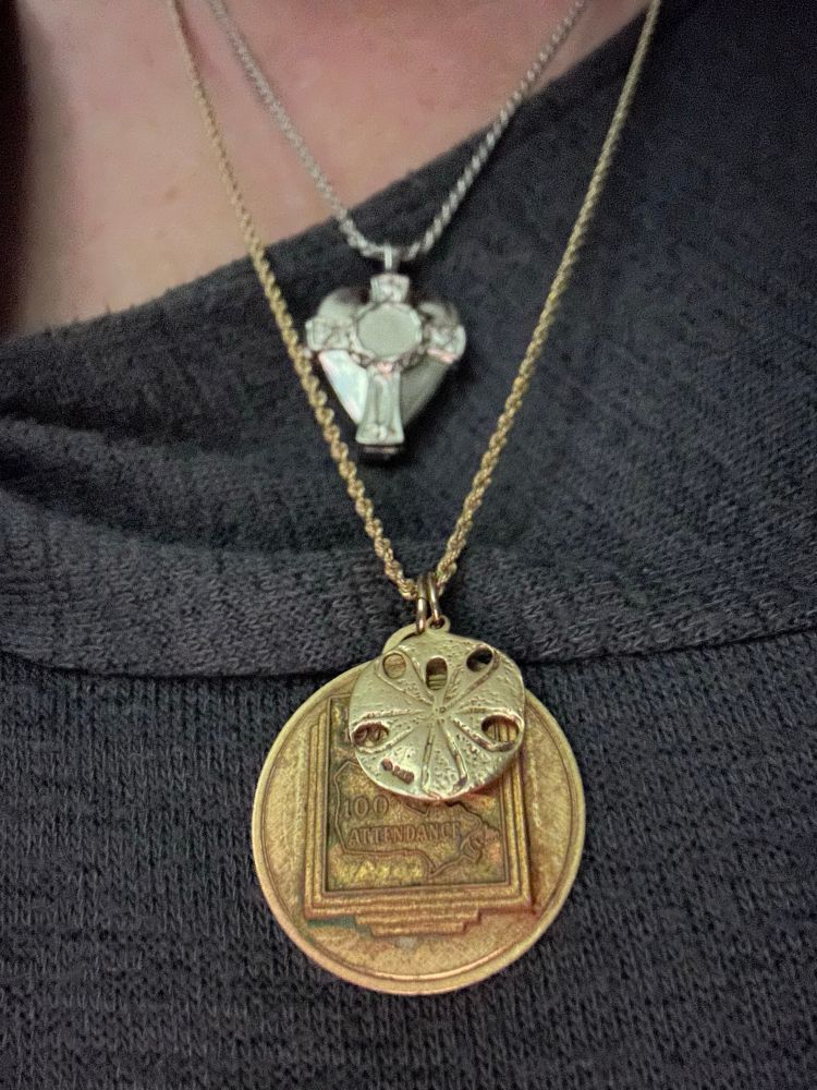 Lions emblem on necklace with shell charms and urn of Celtic cross