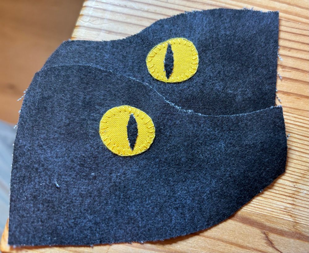 Two pieces of fabric each with a yellow eye with vertical pupil