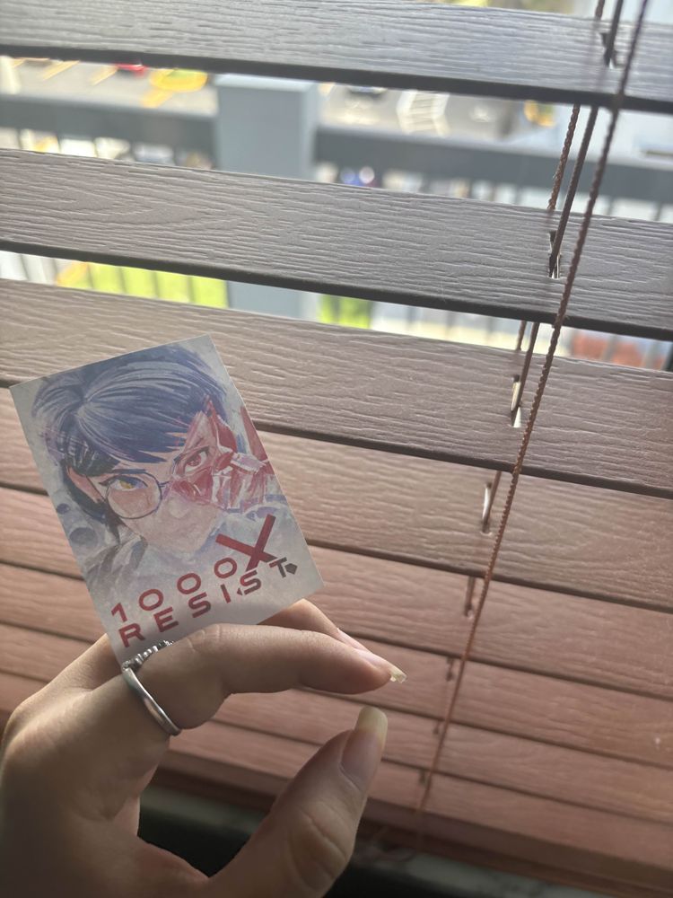 A hand holding the 1000xRESIST keyart like a cigarette