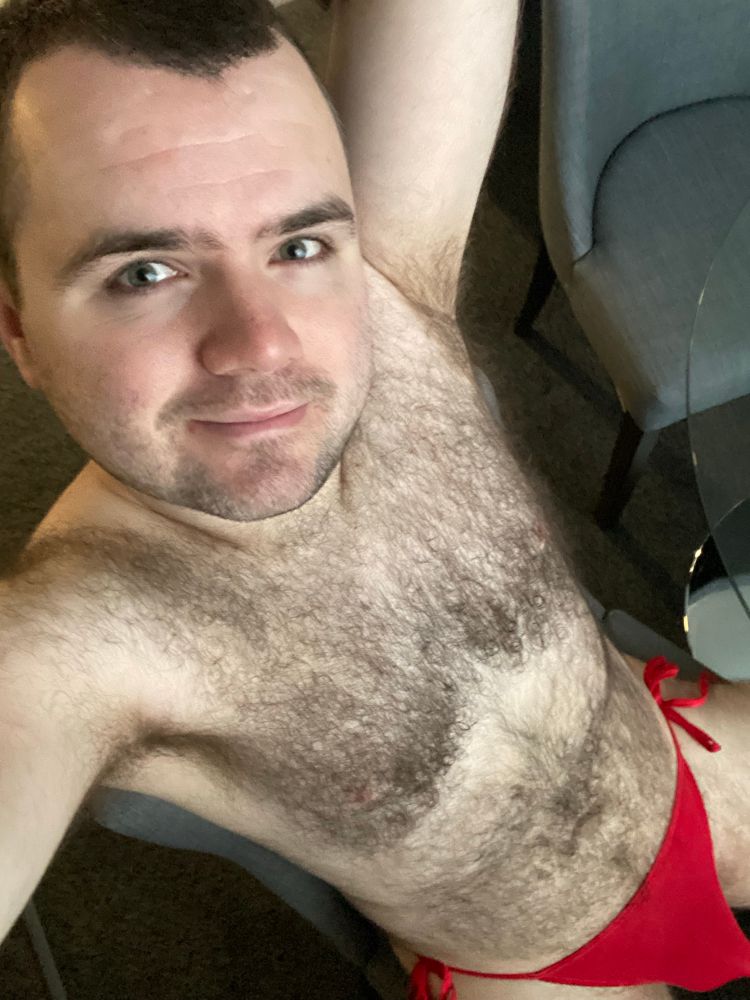 Sitting on chair in just a red tie up thong. 