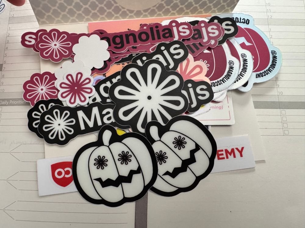 A pile of conference stickers on top of a handwritten note. There are so many stickers that you can’t see a single bit of the content of the note behind it. 