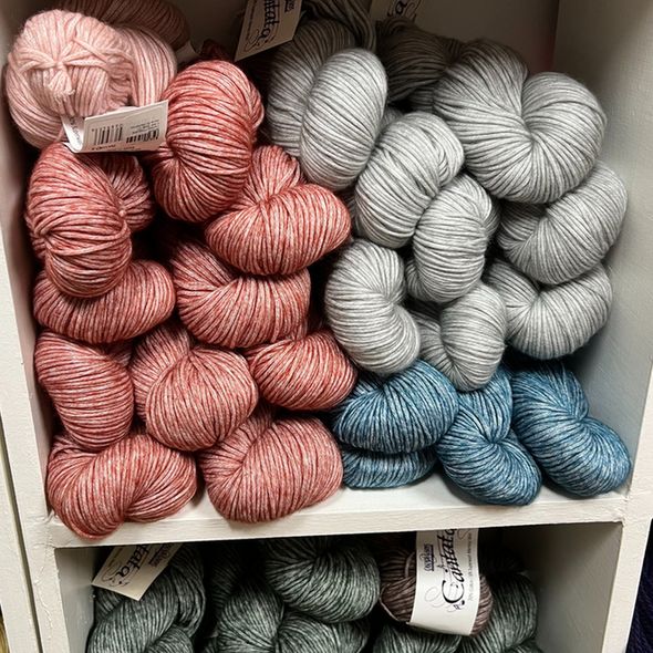 Cascade Yarns' Cantata in shades of green, gray, blue, and red are on display.