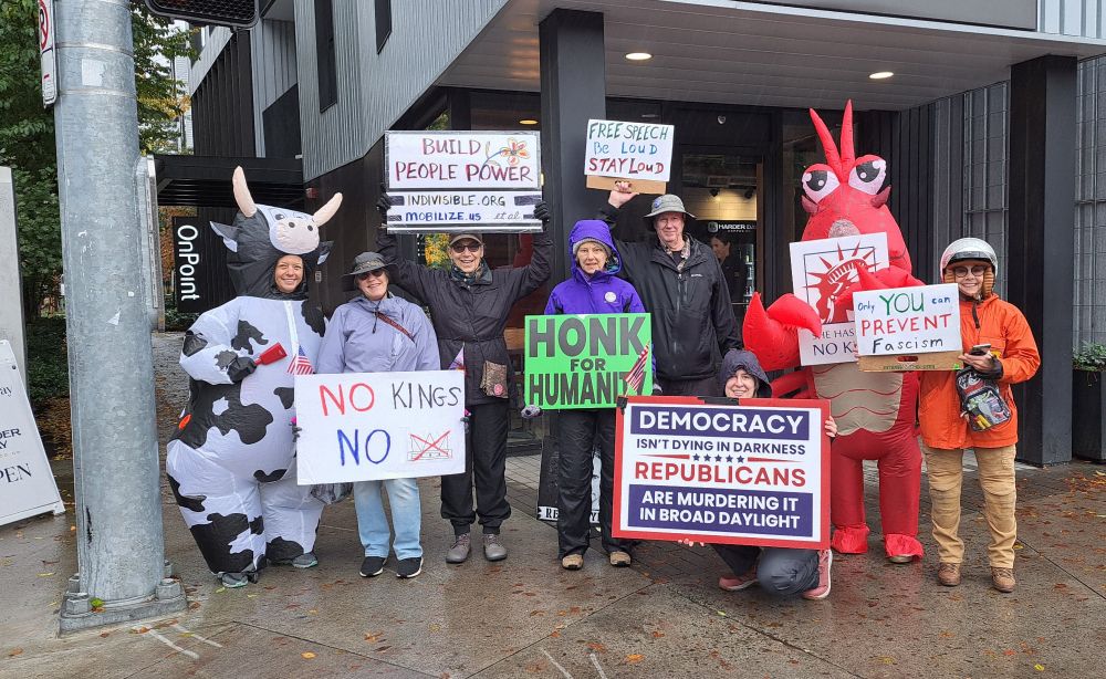 People in rain gear or costumes holding signs such as: 
Honk for Humanity