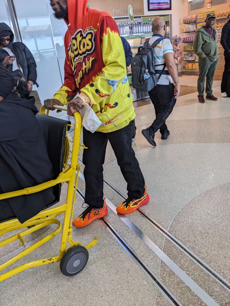 Wheelchair porter in Cheetos hoodie with complement orange flame shoes 