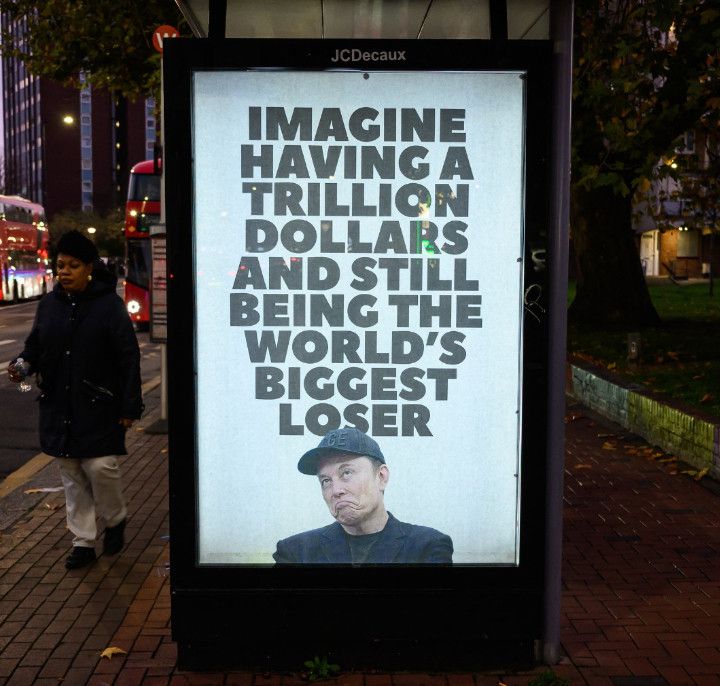 Photo of an outdoor advertising panel on the side of a London bus-stop, which has been subverted, brandalised - the large poster in the panel has these words above a picture of Musk:
"Imagine having a trillion dollars and still being the world's biggest loser".