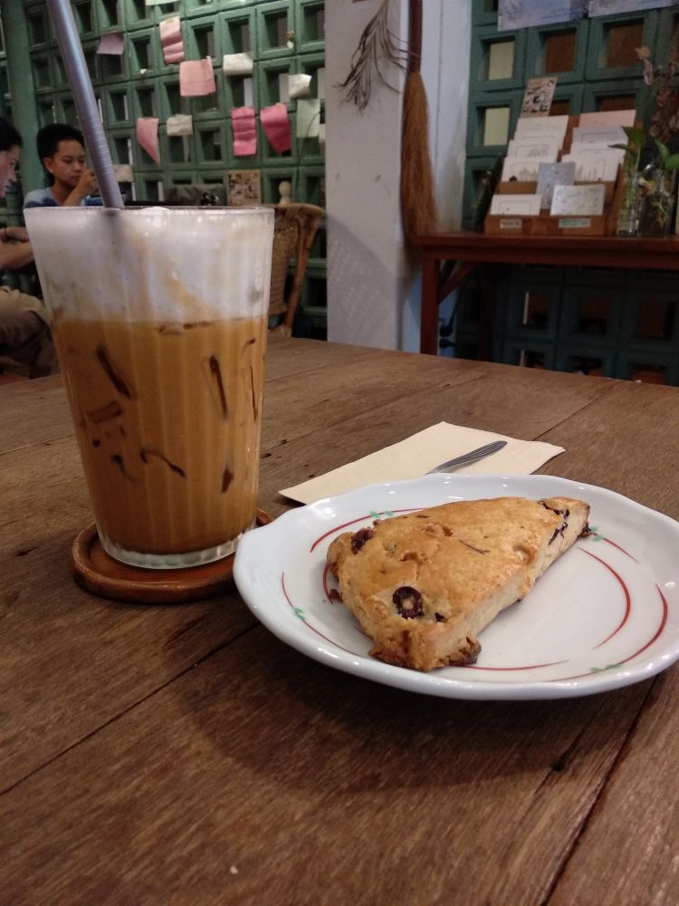 A glass of iced Thai tea and a piece of biscuit