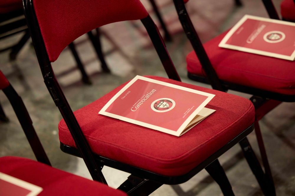 Red chairs arranged in a row, each with a copy of the Convocation program on the seat.