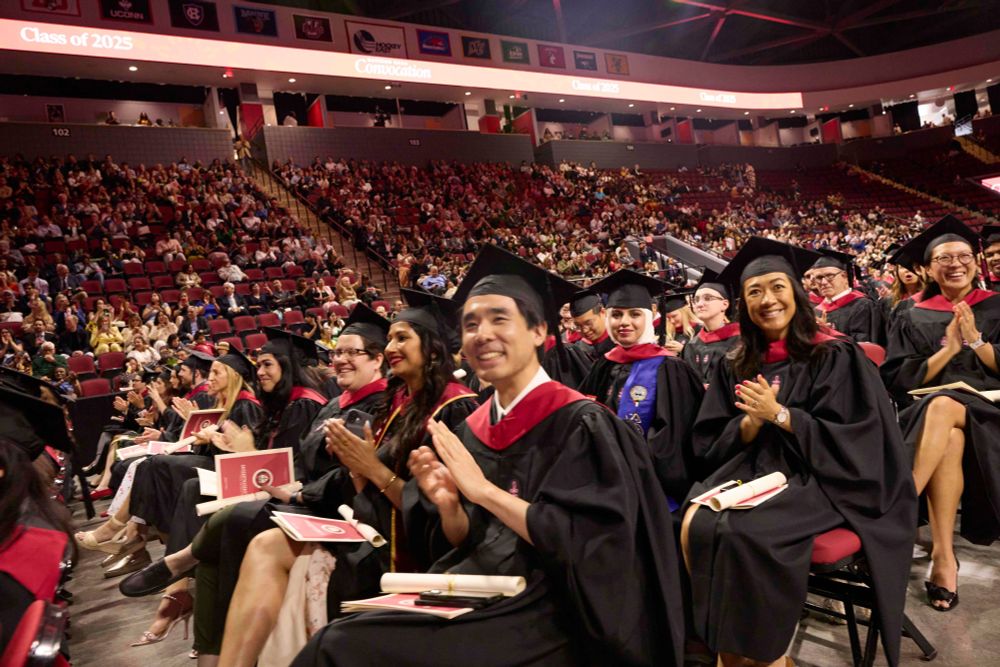 Graduates in caps and gowns clapping joyfully during the 2025 Convocation ceremony, with a large audience in the background in an auditorium.